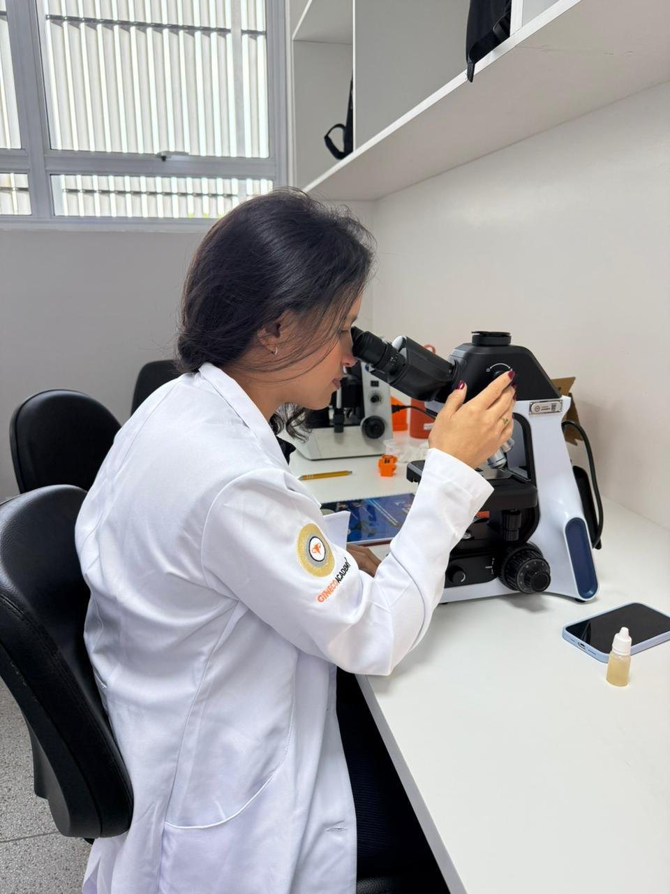 Dra. Mirna observando uma amostra ao microscópio